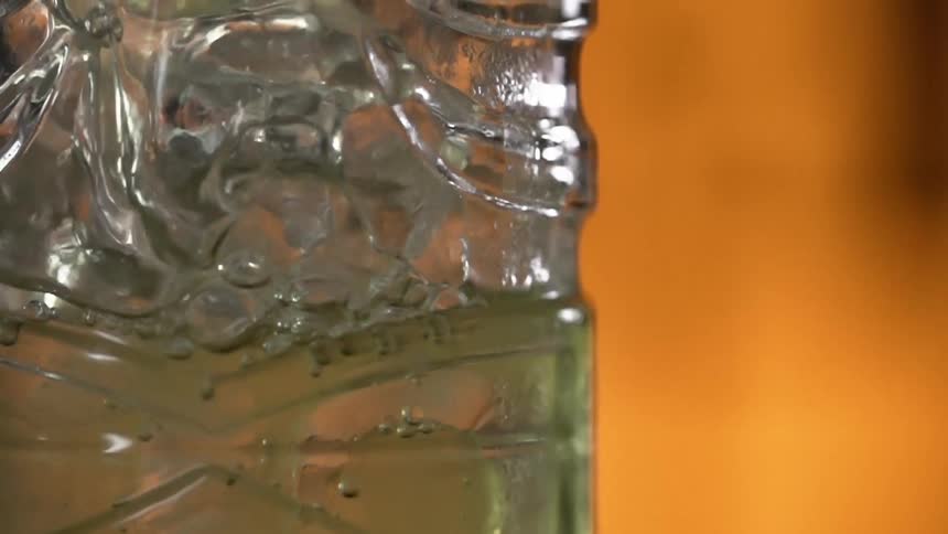 A liquid being poured into a glass with ice