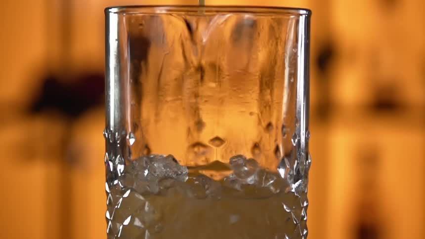 A cocktail being made in a glass with ice