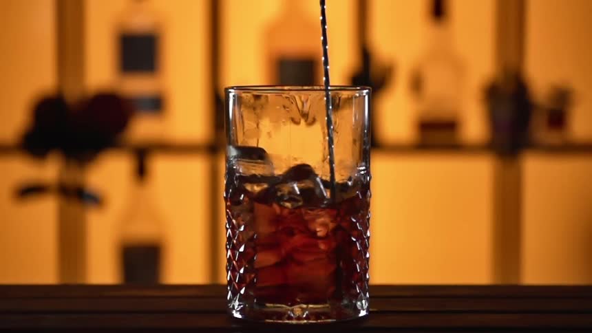 Cocktail stirrer mixing a drink at bar counter