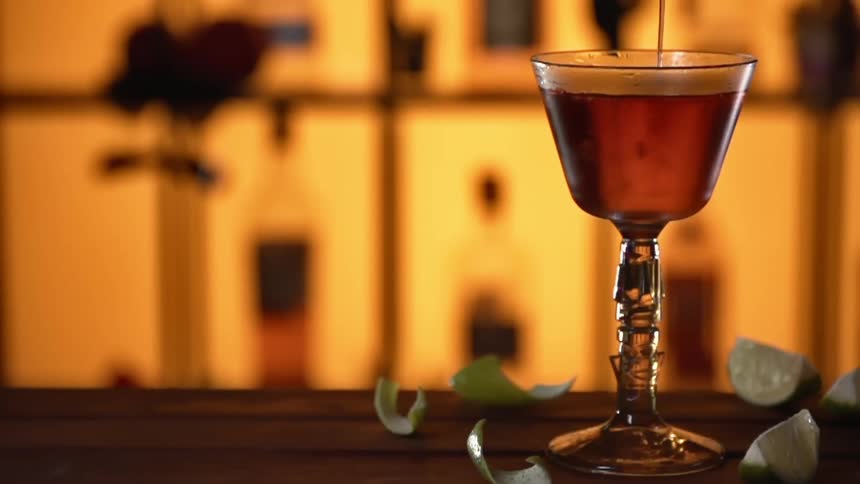 Red liquid poured into a glass with lemon slices around