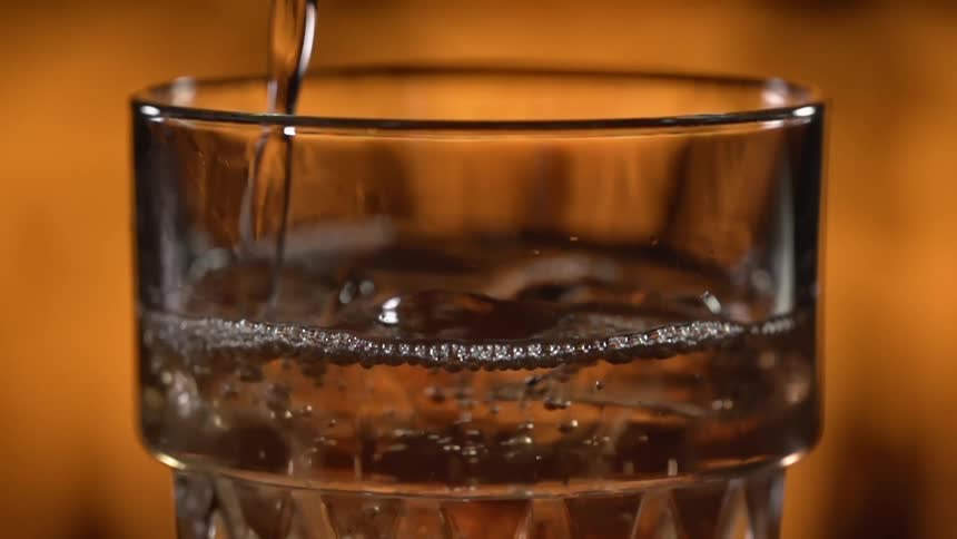 A beverage is poured into a cup with ice