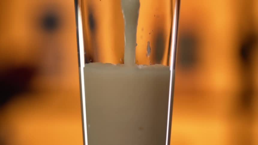 A thick yellowish white liquid is being poured into a glass