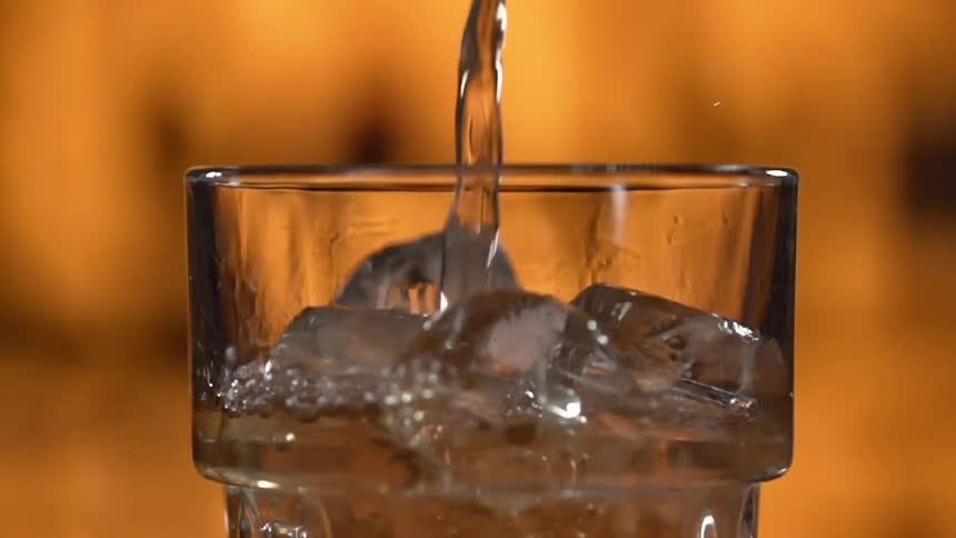 Water being poured in a glass with ice during a photo shoot