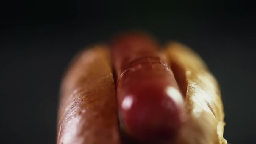Sausage being dropped inside a hot dog bun