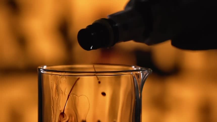 Silhouette of liquid pouring from a bottle into a glass jar