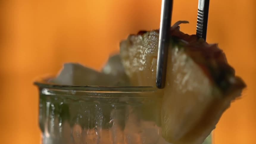 A wedge of pineapple is placed on the drink glass