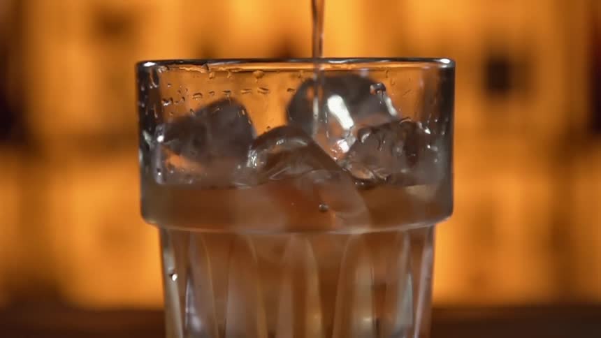 A beverage is poured into a glass of ice