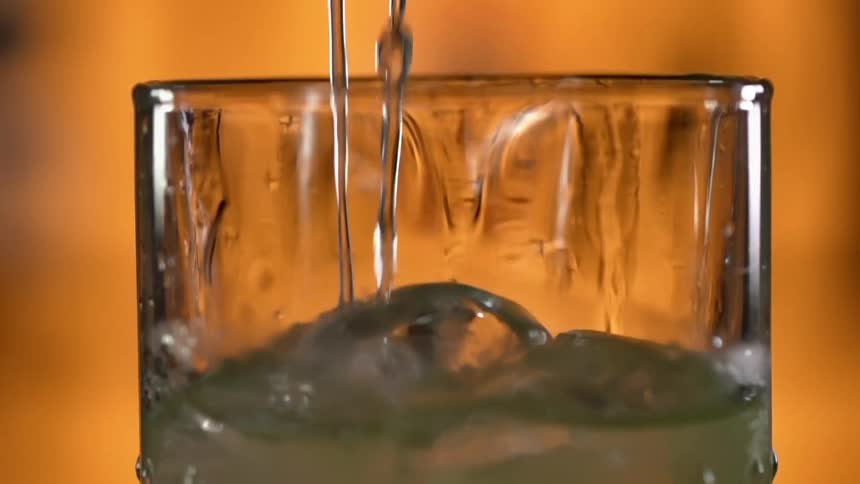 Liquid being poured into a glass with ice