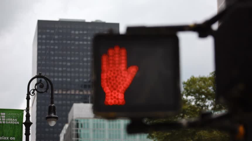 A lit up do not walk traffic sign in front of office buildings in a downtown area