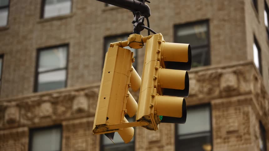 A hanging traffic light at an intersection in a city during the day