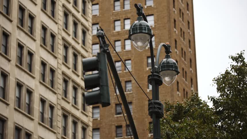 A traffic light and dual lamp post sit at an intersection near tall apartment buildings