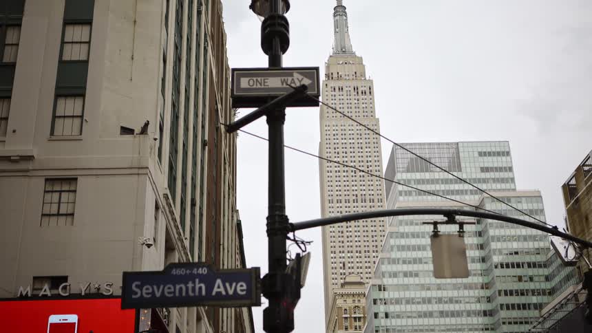 Lamp post with street signs in front of the empire state building in new york city