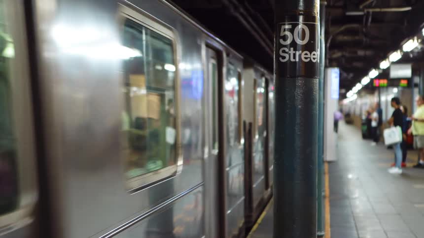 People standing in a subway station as a subway goes past
