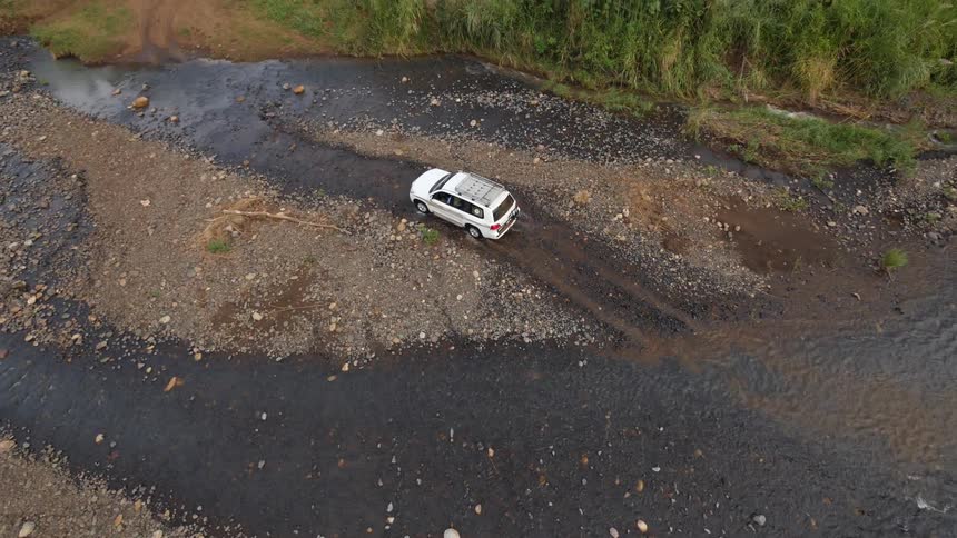 A jeep driving in a shallow riverbed