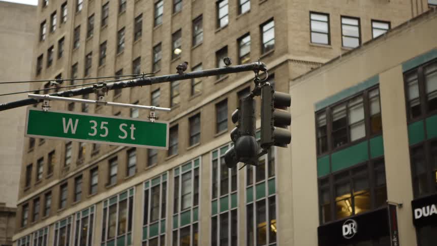 A hanging traffic light at an intersection in a city during the day