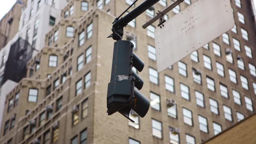 A traffic light hands next to a sign in a downtown area of a city