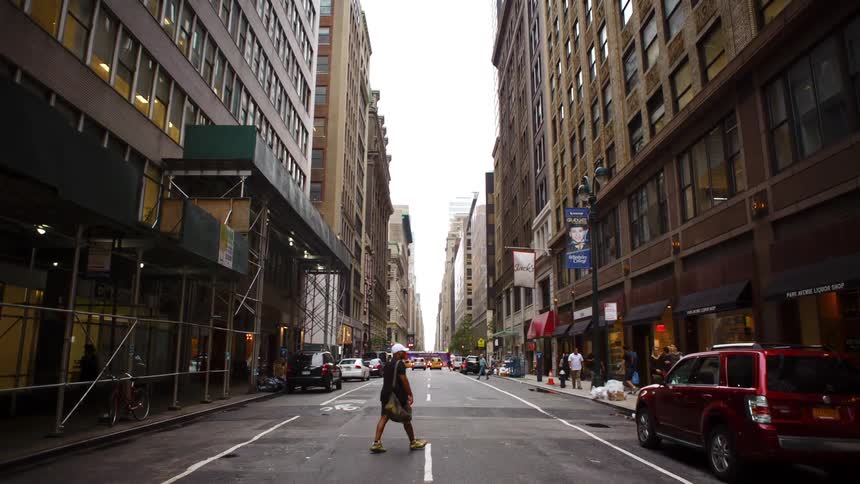 A man jaywalks across a two lane street downtown