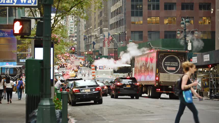 Traffic and pedestrians move around a busy intersection in a metropolis during the day