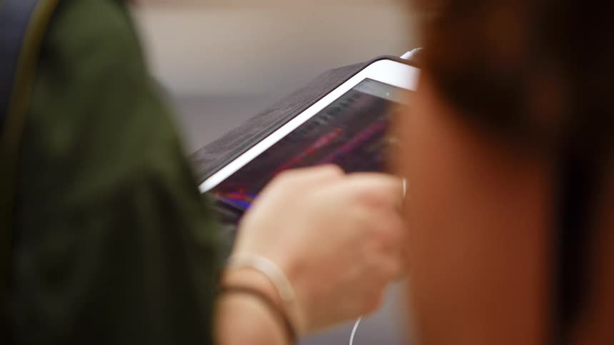 A person browses images on a tablet in the street