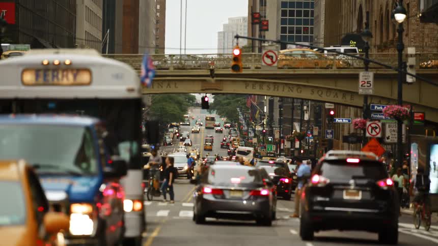 Pedestrians cross the street at a busy intersection filled with traffic in a city