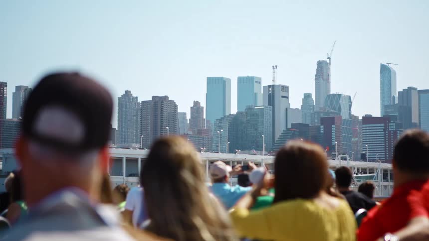 People on a tour boat with buildings skyscrapers and the sky in the background