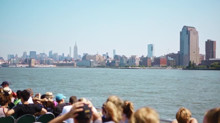 Passengers watch big city skyline with tall buildings and skyscrapers as traveling by a ferry across a river