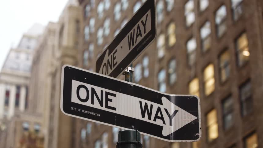 A traffic sign on the corner of a metropolis during the day