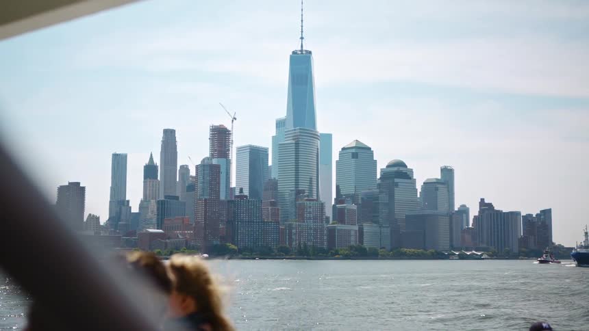 People on a boat look across the water and at a city skyline