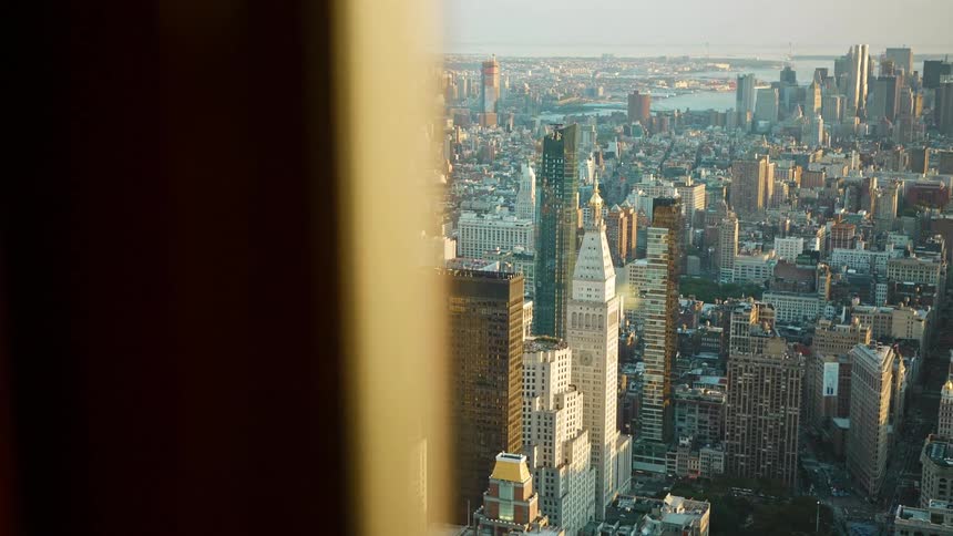 A window in a high rise building has close up views of the city below