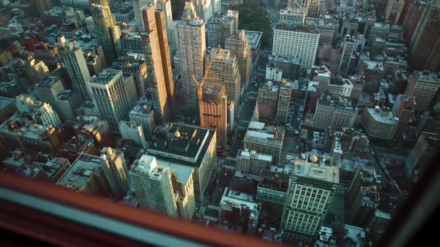 A wide street and skyscrapers in a city seen from the above from the window of an even taller building
