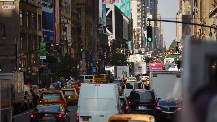 Busy city street with heavy traffic and pedestrians walking down the street