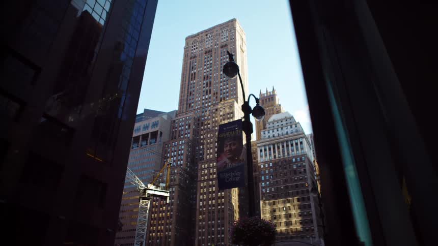 A city street with a streetlight with buildings and skyscrapers in the background
