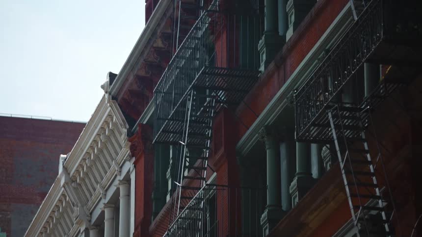 A city with buildings with fire escapes with the sky and clouds above