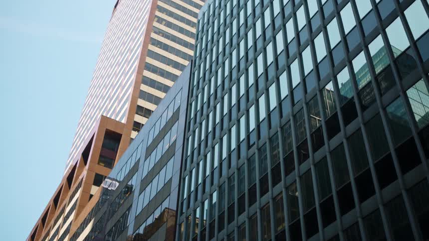 Buildings are reflected off the mirrored windows of a high rise in a city