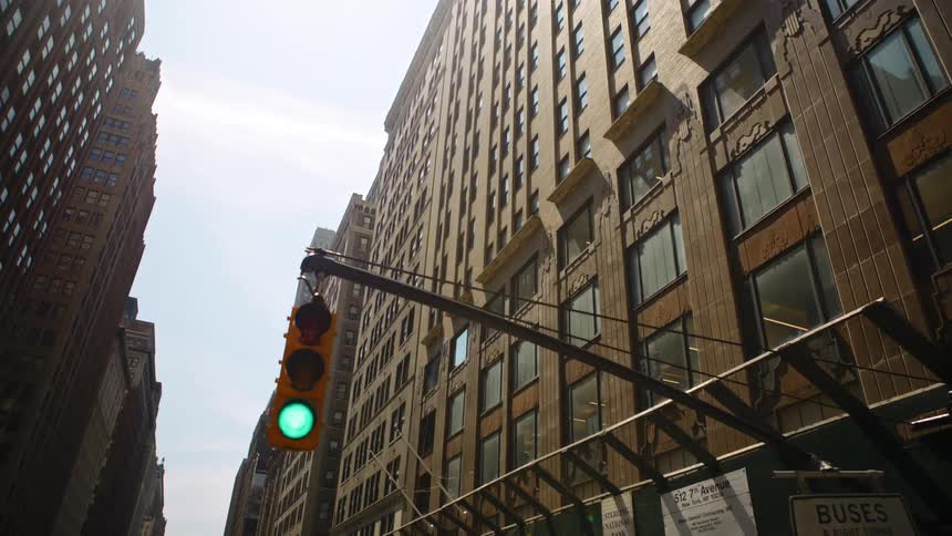 Green traffic light in front of tall skyscrapers in city downtown