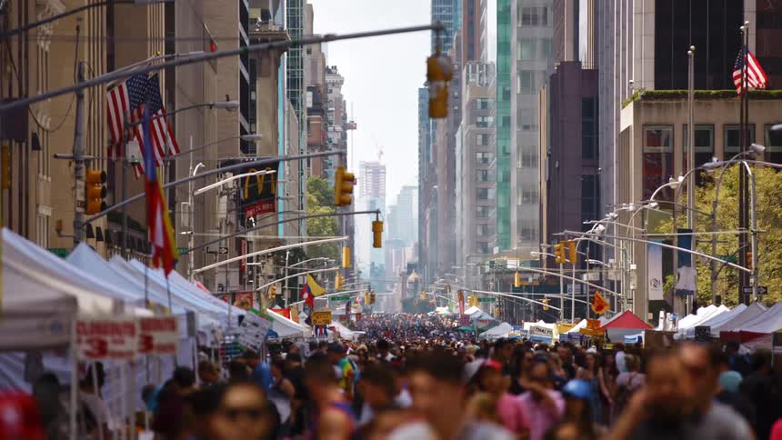 Large crowd walks down a city street near the buildings