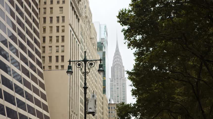 A skyscraper in a metropolis looms over other tall buildings while shrouded in light fog