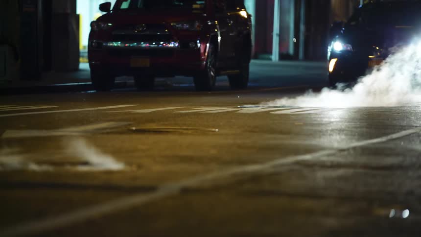 A car drives down the street at night
