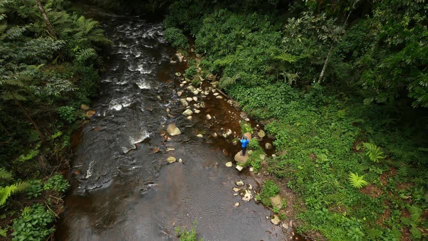 Aerial view of a man photographing a stream below