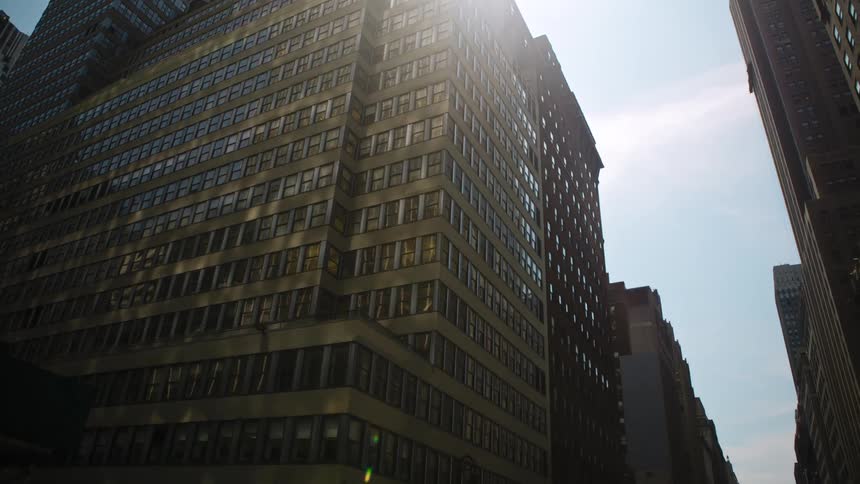 The sun reflects off windows of tall office buildings and apartments in a city