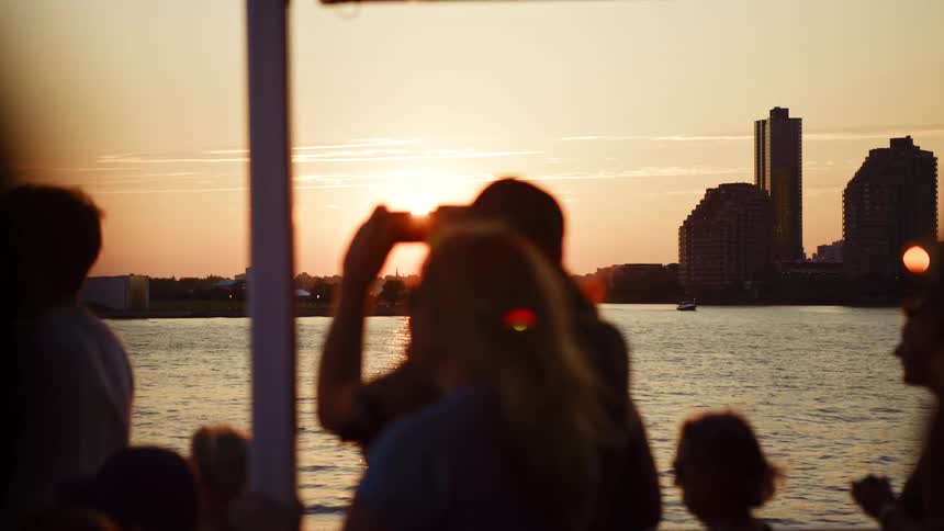 Tourists travel on a boat in the river near the city as they take photographs