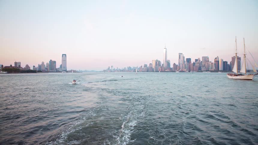 Boats move through a bay outside a large urban downtown area