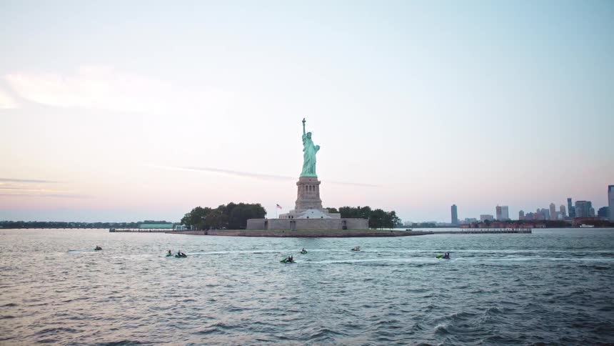 People ride on jet skis near the statue of liberty