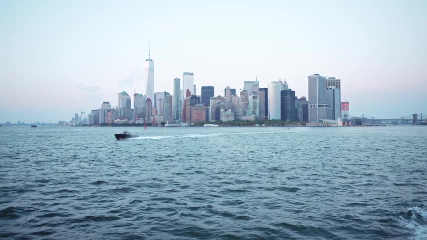 Big city skyline from a distant with multiple tall buildings and a bridge seen from sea on the horizon