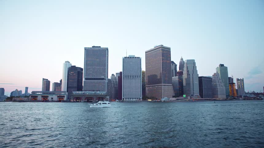A large boat sails through the ocean in front of a city
