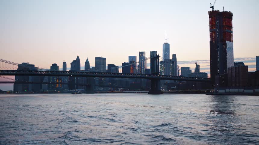 Brooklyn bridge in new york city from a boat in the river at sunset
