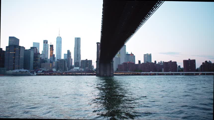 A bridge over a river with buildings and skyscrapers and the sky in the background
