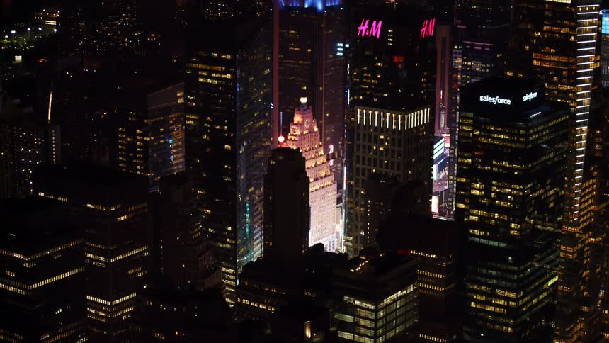 A skyscraper is lit up with pink lights at night
