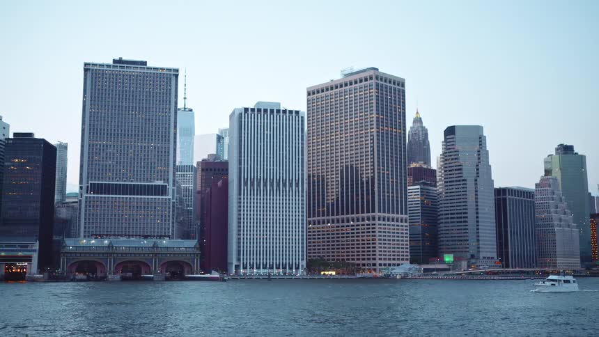 City skyline with tall buildings by a river at dusk