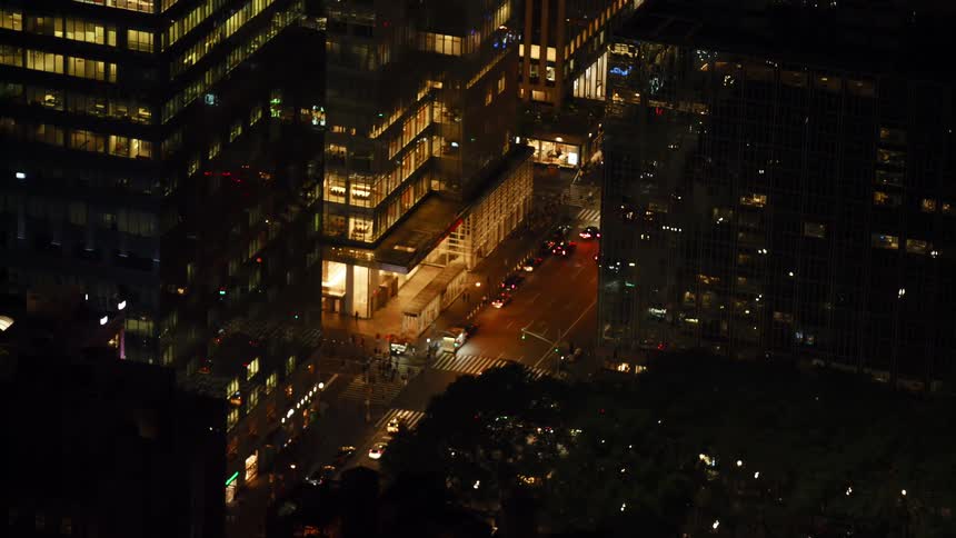 People and traffic move along a downtown city street at night